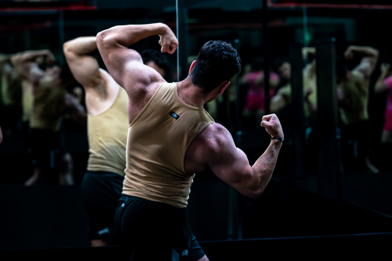 Lifter hitting a back double-biceps pose in the gym mirror